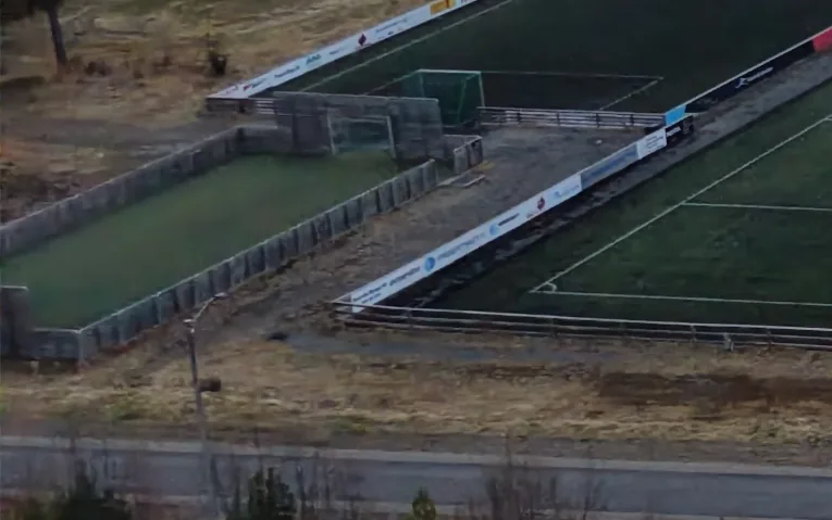 Ballbingen med gjerde rundt, ved siden av den mindre banen