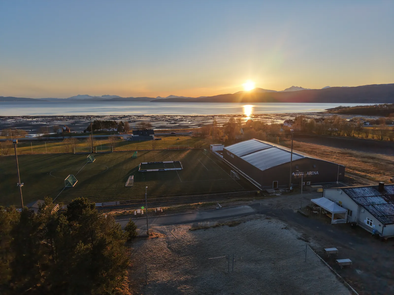 Banen og Idrettsheimen sett fra lufta med fjorden bak