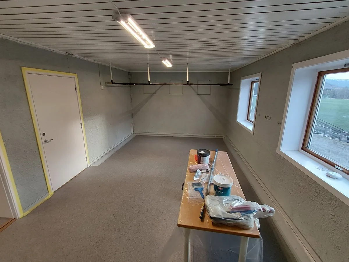 Tilstøtende rom under oppussing med malingsspann på bordet