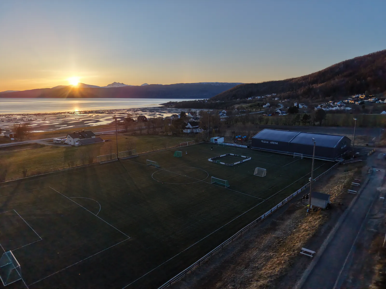 Banen og hallen i kveldslys med fjorden bak