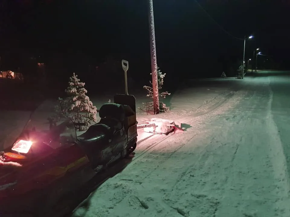 Snøscooteren med røde lys i løypa om kvelden